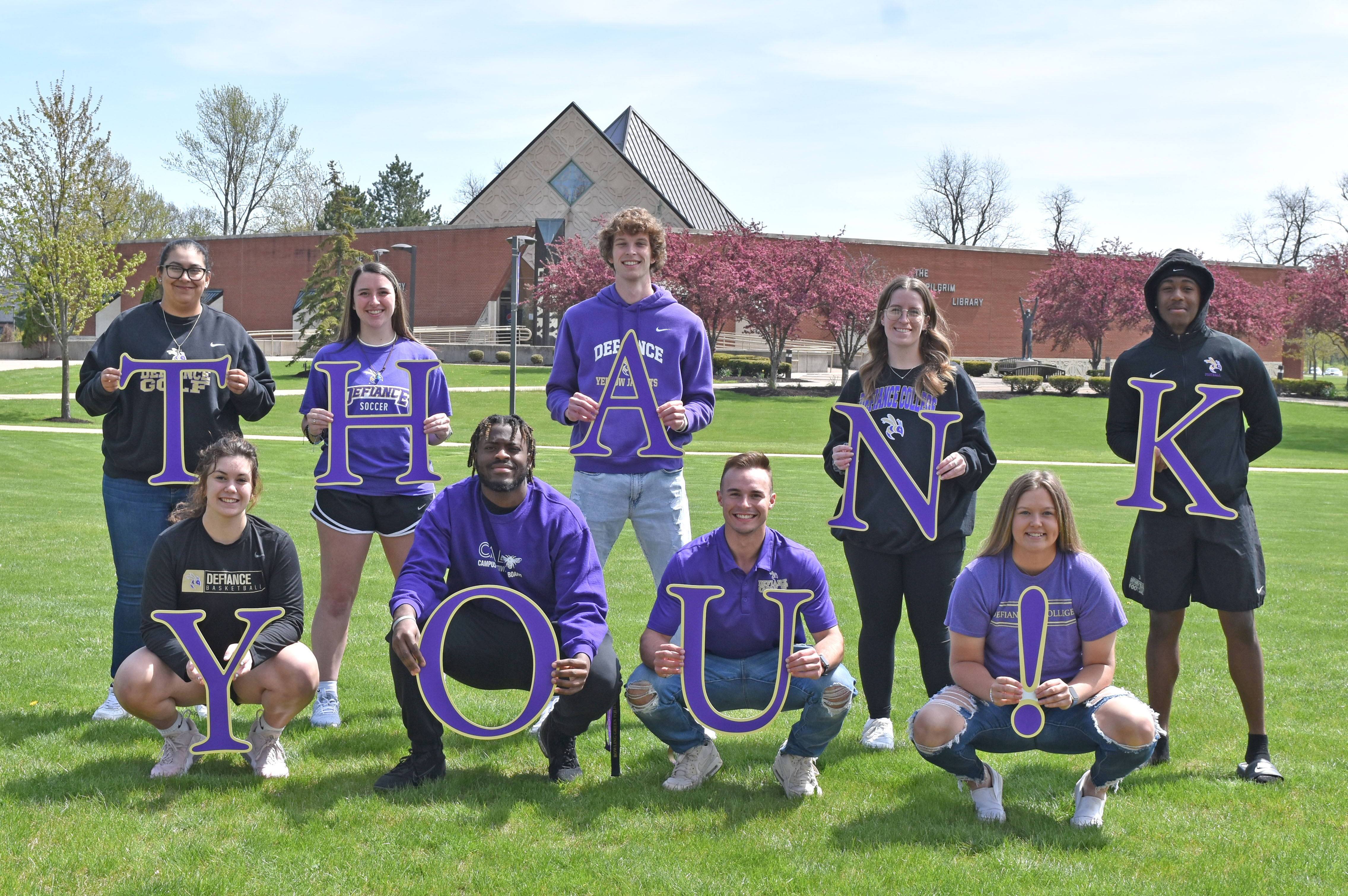 Group of students in front of Pilgrim Library holding letters that spell out thank you.